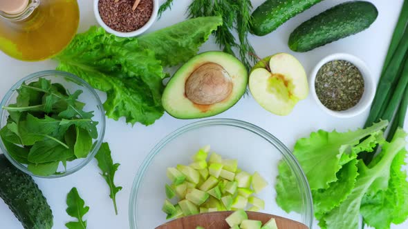 Woman Cooking Salad of Fresh Green Vegetables and Herbs