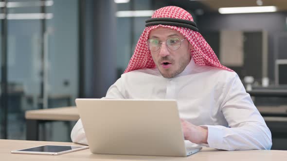 Middle Aged Arab Man with Laptop feeling Shocked