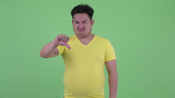 Stressed Young Overweight Asian Man Giving Thumbs Down