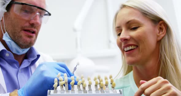 Dentist showing teeth shades to female patient