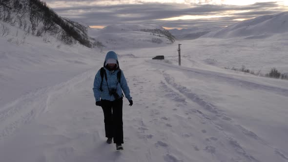 Girl walking on a snow in high winds, Kvaloya, Arctic, Norway