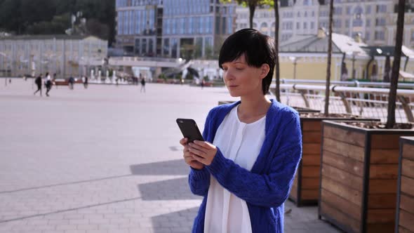 Beautiful Girl Is Standing on the Street with Phone