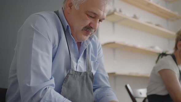 Portrait of a Male Potter Making a Ceramic Plate in Slow Motion alt