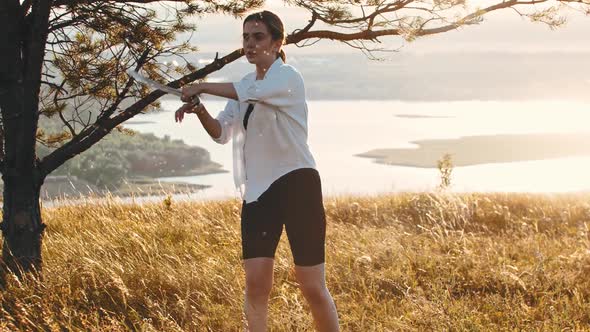 Young Woman Training with Swords on the Hill  Midges Flying Around