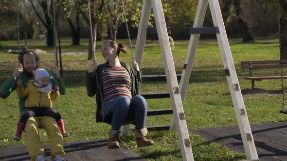 Family playing together at swing in public playground, Zagreb, Croatia.