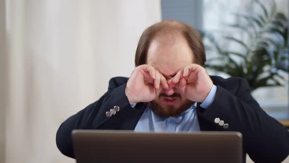 Stressed Male Entrepreneur Covering Face with Hands at Workplace Tired After Using Laptop