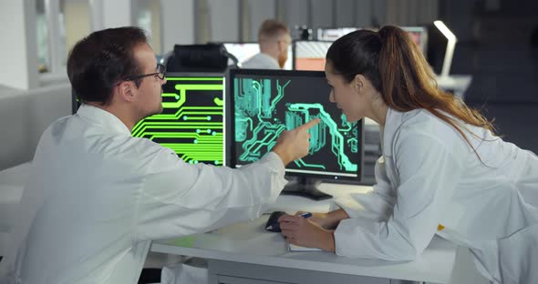 Female Engineer Helping Colleague with Detail Drawing on Computer