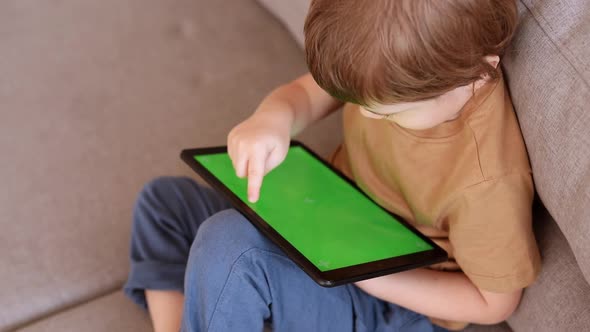 Preschool Caucasian Boy Tabs on the Green Screen of Tablet PC