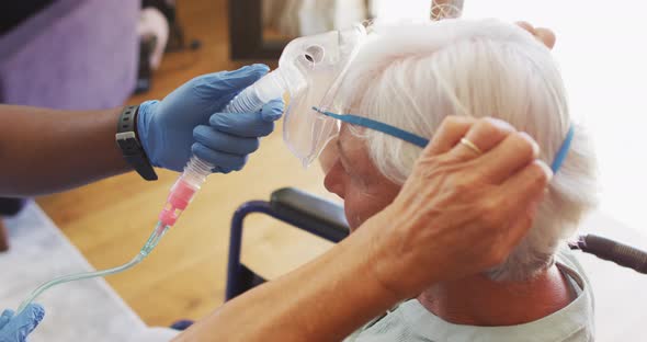 Video of hands of african american male doctor keeping oxygen to caucasian senior woman