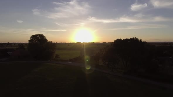 A drone shot flying upwards and panning down, with the sun going down behind a church