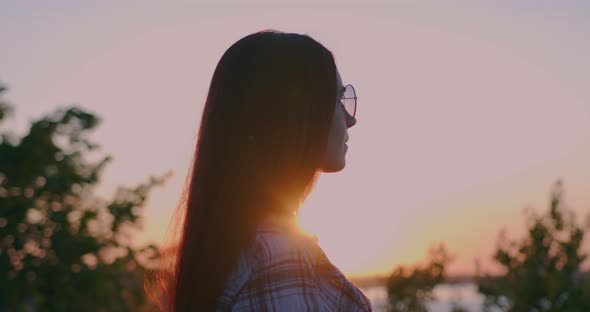 Young girl on the background of sunset looks into the distance