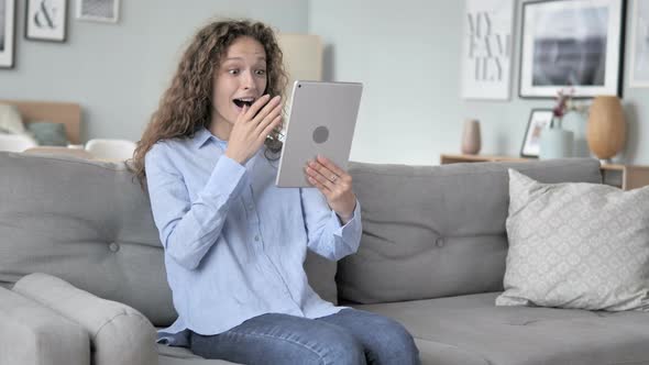 Relaxing Curly Hair Woman Celebrating Success on Tablet