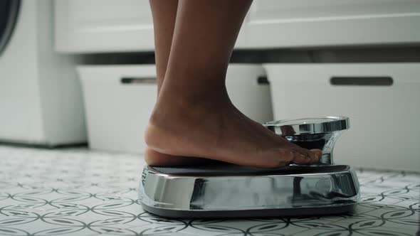 Feet of unrecognizable African-American woman stepping on the bathroom scale. Shot with RED helium c