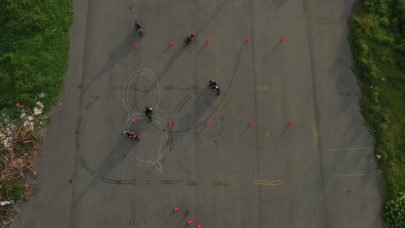 top down wide aerial view of riders practicing on an advanced motorcycle training slalom course betw