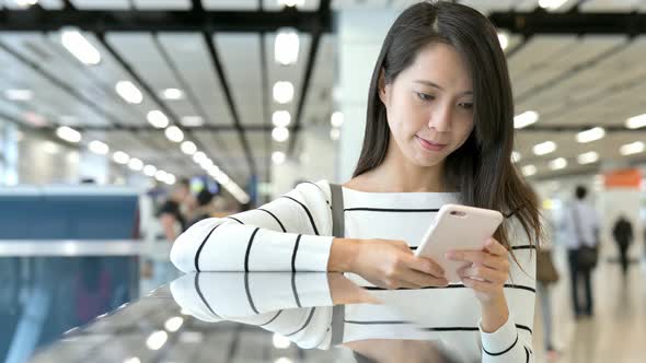 Young Woman working on cellphone in station hall 