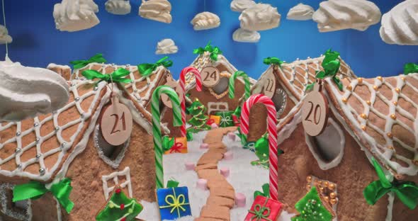 Christmas gingerbread cottage and meringue clouds on blue sky.