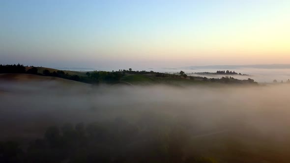 Fog filled landscape on a cold morning in the Tuscany countryside Italy, Aerial drone flyover reveal