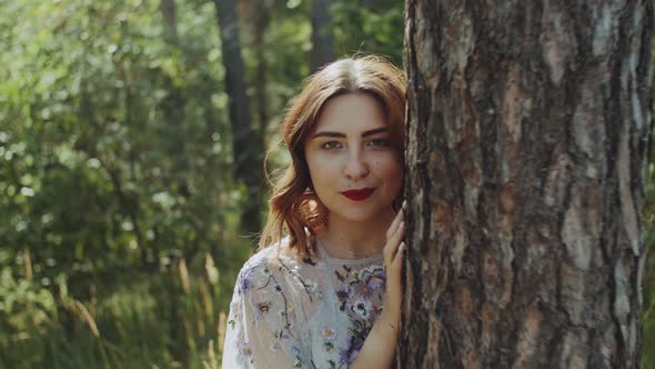 Portrait of Beautiful Young Caucasian Woman with Red Lips Posing in the Forest Near Tree Bark