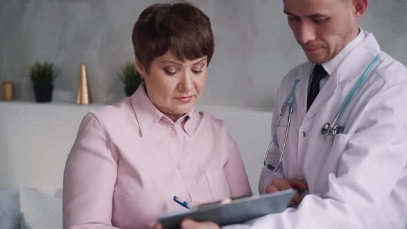 Doctor Sign Blank Form with His Patient at Home