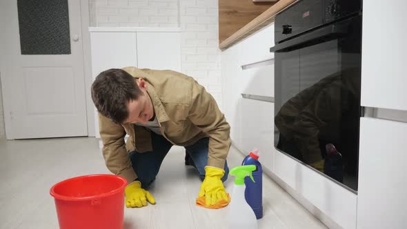 Man Cleans Floor with Detergent and Water in Kitchen