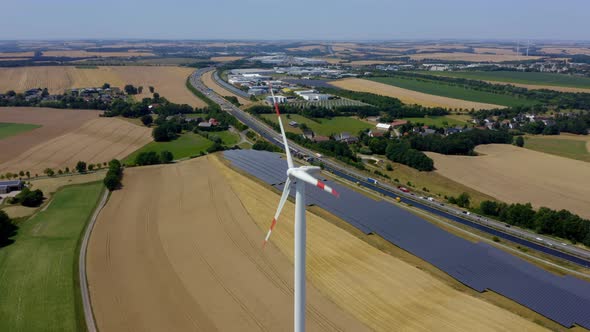 Solar panel cells and rotating wind turbines on the green energy farm. 