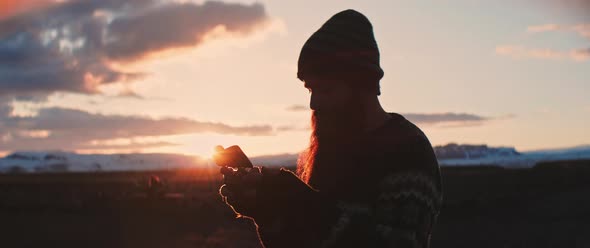 Man uses his phone during sunset