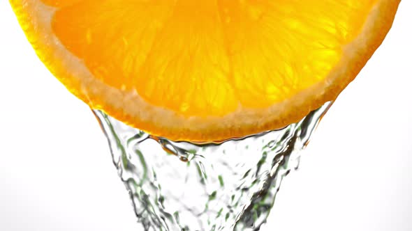 Super Slow Motion Macro Shot of Flowing Water From Fresh Orange Slice on White at 1000Fps