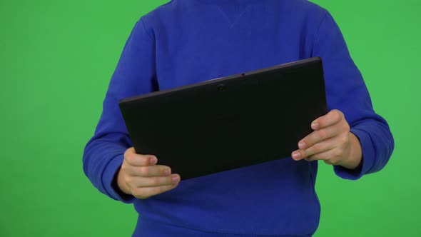 A Young Boy Plays a Game on a Tablet - Closeup - Green Screen Studio