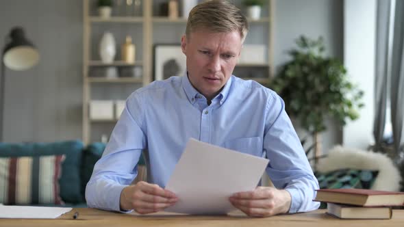 Businessman Upset After Reading Documents at Work