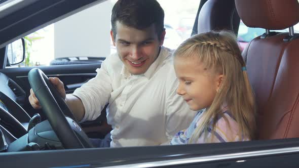 Little Daughter and Father Sit in the Car and Talk