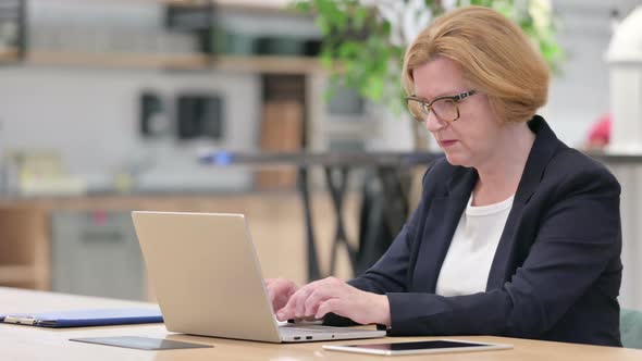 Old Businesswoman Celebrating Success on Laptop in Office