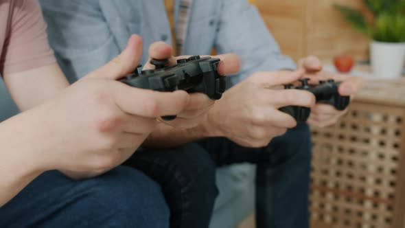 Closeup of Hands Kid and Adult Playing Video Game Using Joysticks on Couch at Home