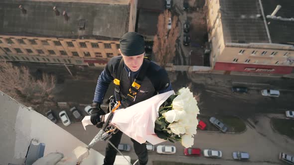 Lose View of Male Professional Climber in Uniform, Hanging at Height on Cable Above High-rise