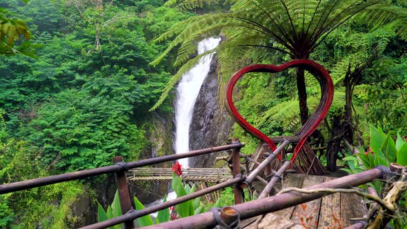 Dolly shot of romantic wooden heart with epic waterfall in background.Balo,Indonesia.