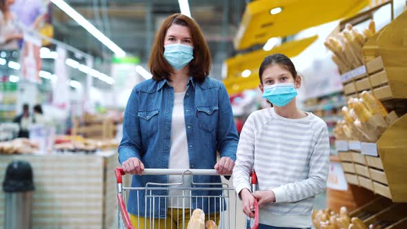 Mom and daughter posing with shopping cart at grocery store during COVID