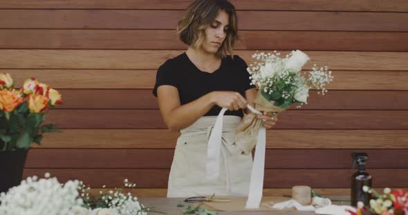 Young woman florist preparing flower bouquet