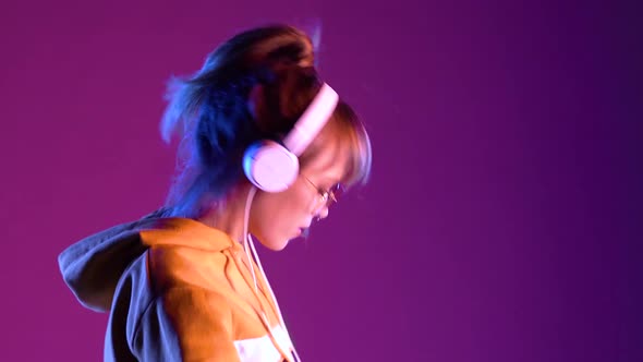 Teen Girl Wear Headphones Listen Music Dancing on Purple Neon Studio Background
