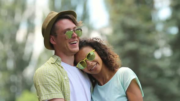 Couple in Love Laughing and Hugging in Park Her Arms Wrapped Around His Neck