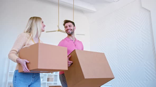 Amazed couple in love guy and lady carry brown cardboard boxes