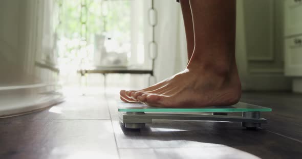 Woman checking her weight on weighing scale at home 4k