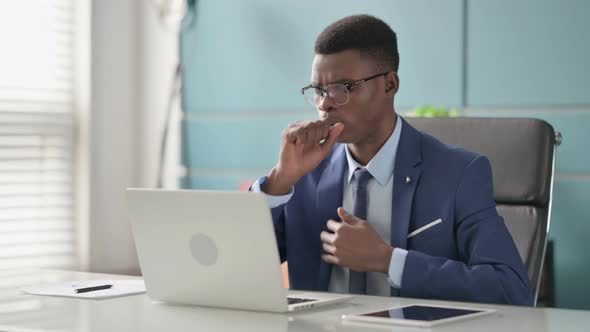 Young African Businessman Coughing While Using Laptop in Office