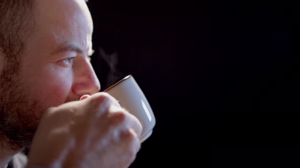 BACKLIT - A man drinks from a steaming cup, suitable for multiple uses