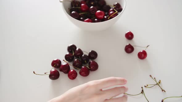 Lady hands take red cherry from white bowl young woman eats