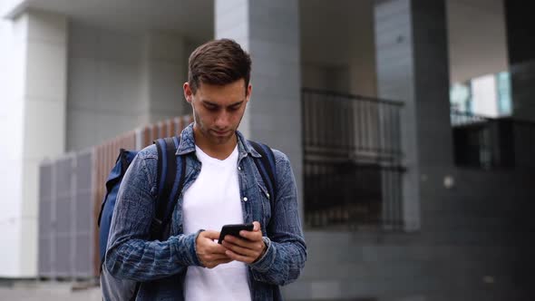 Closeup of Serious Delivery Man with Thermo Backpack Using Navigation App on Mobile Phone to Search