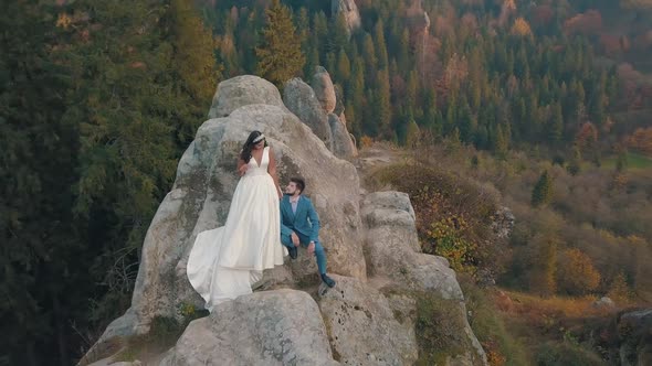 Newlyweds Stand on a High Slope of the Mountain. Groom and Bride. Arial View