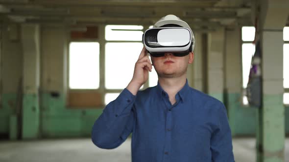 A Modern Engineer Wearing Virtual Reality Glasses Inspects a Construction Site