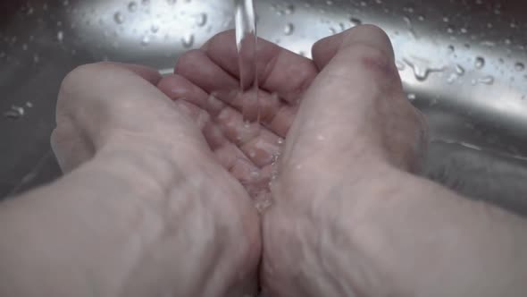 Stream Of Water Falls From A Tap On The Hands And Scatters Lots Of Drops 2