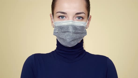 Portrait of Young Woman in Protective Medical Mask Looking at Camera, Isolated