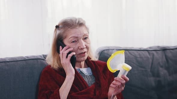 Lonely Senior Woman Holding Oxygen Inhaler and Having Phone Conversaion