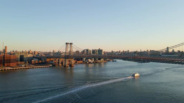 Aerial view following a ferry on the East river, sunset in NYC, USA - pan, drone shot